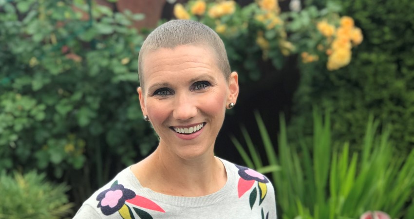 A white woman with a shaved head in a garden